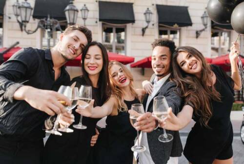5 Freunde machen ein Spaßfoto vor der Fotobox mit Sektgläsern in der Hand